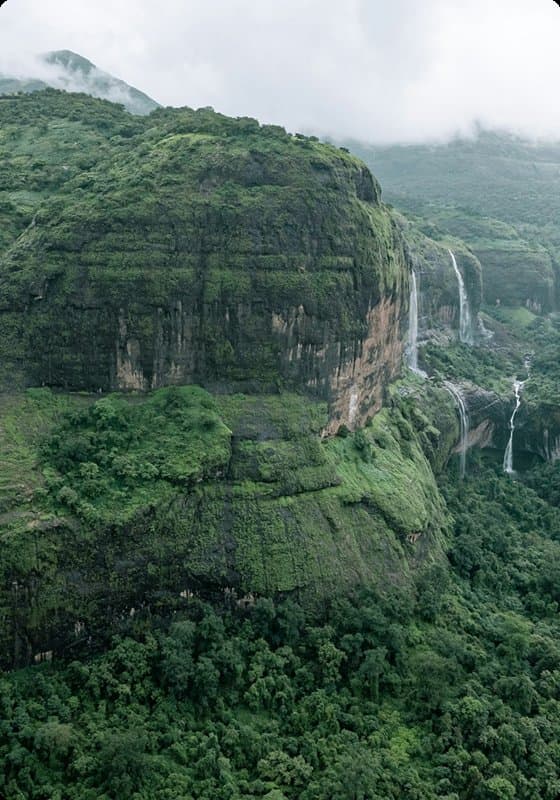 Green cliff face with a waterfall in the monsoon
